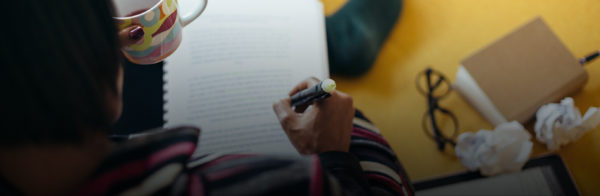 A person highlighting notes and drinking tea