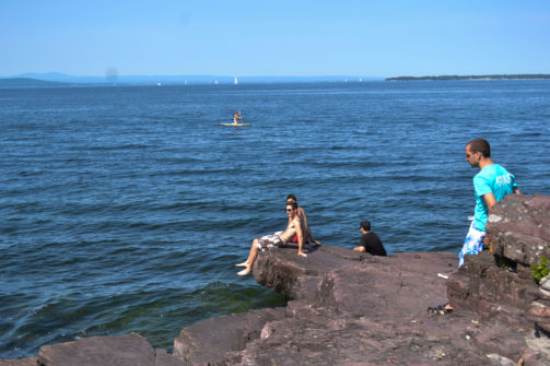 people chilling on rocks at the waterfront