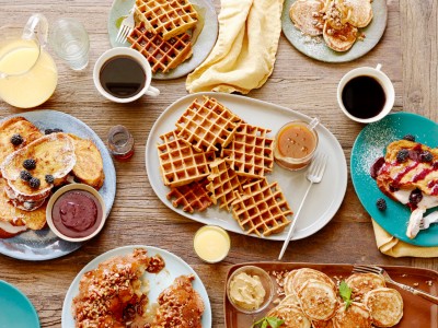 Picture of waffles and other breakfast foods spread on a wooden table