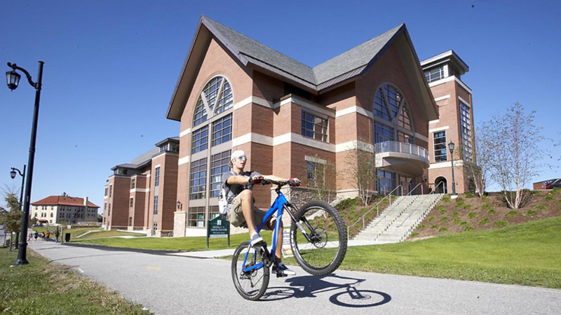 student riding a bike in front of the davis center