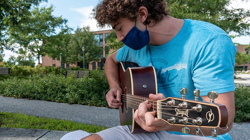 student playing a guitar outside