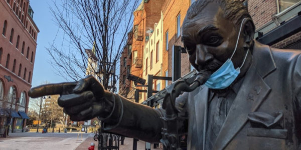 statue of a trumpeter pointing with a mask on