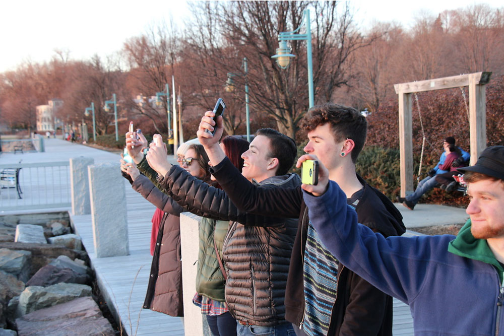 students taking photos of the sunset at the waterfront