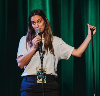 Hannah Berner standing in front of a green curtain holding a microphone