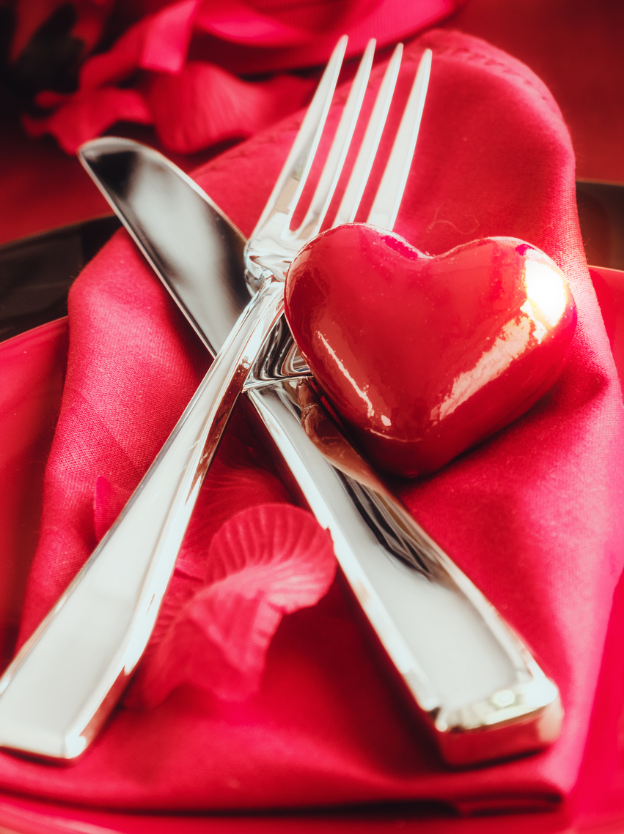 a silver fork and knife placed ontop of a red napkin with a red heart ontop of it