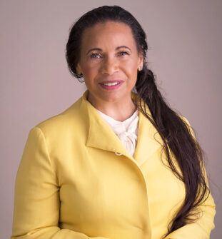 Headshot of Venerable Dhyani Ywahoo. She has long hair pulled pack and is wearing a white shirt with a yellow jacket over it.