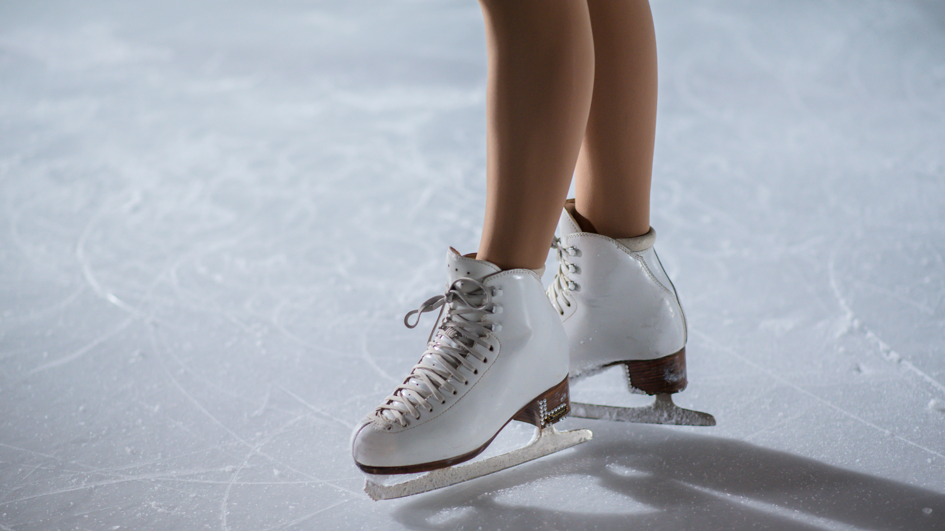 a person wearing white figure skates on ice