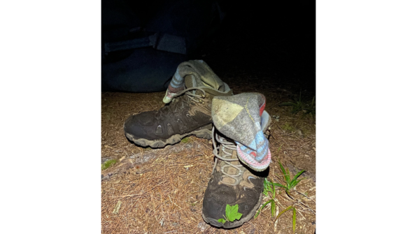 Muddy brown shoes with muddy socks hanging from the sides of the boots
