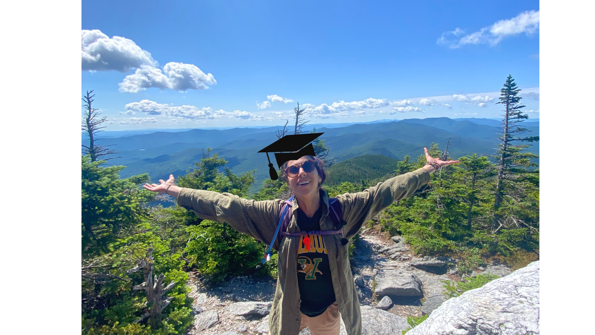 a person in a grad cap with the green mountains in the background